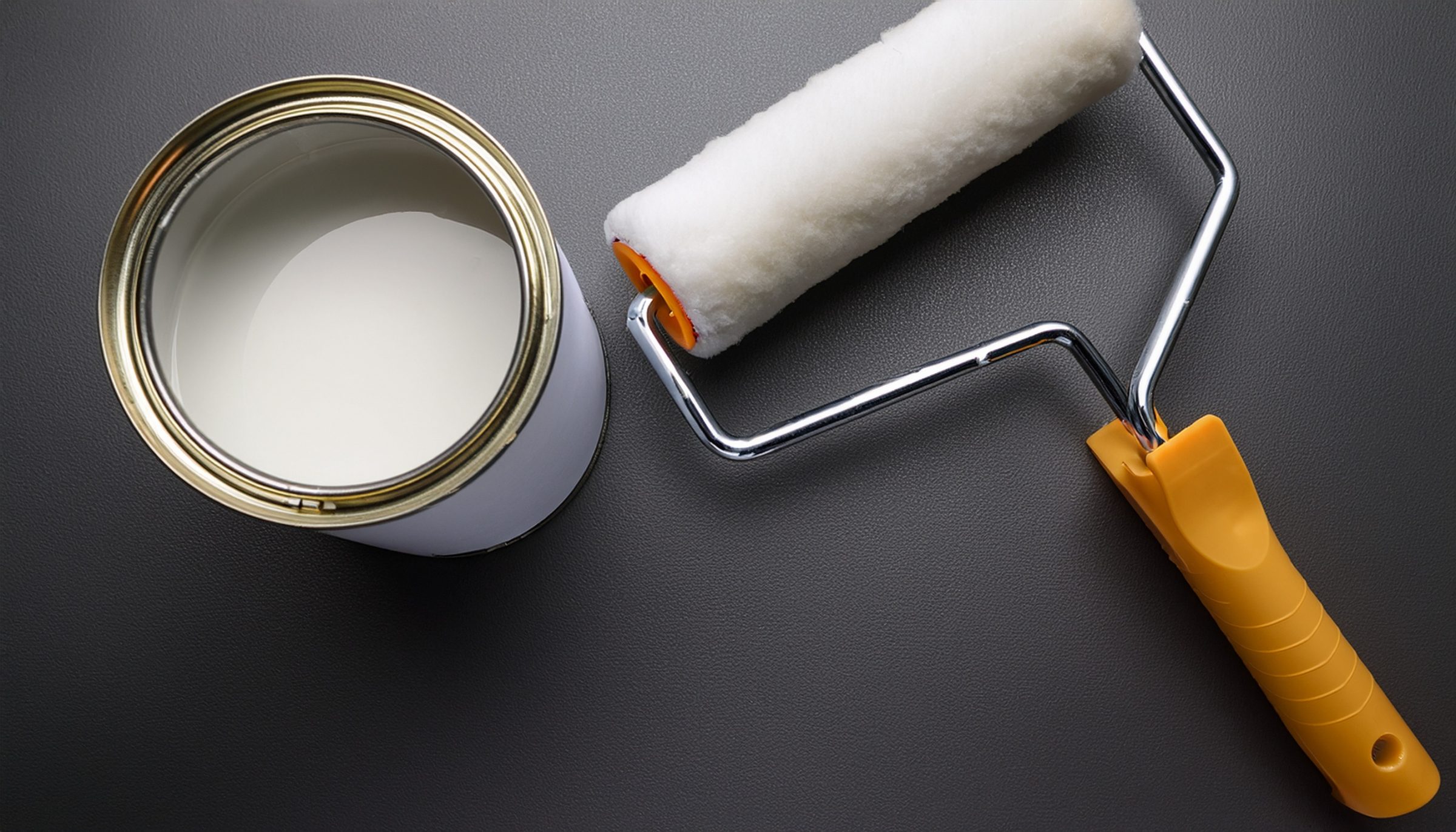 White paint and roller on a black surface.